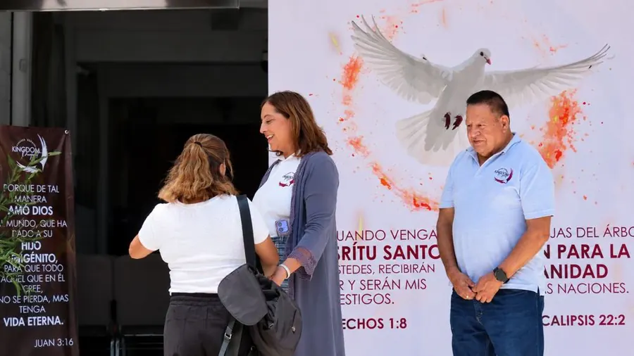 Equipo de bienvenida de Kingdom Project recibiendo a una visitante en la puerta